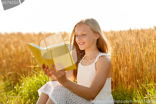 Image of smiling young girl reading book on cereal field