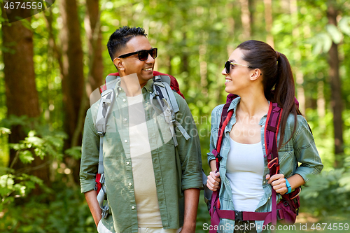 Image of mixed race couple with backpacks hiking in forest