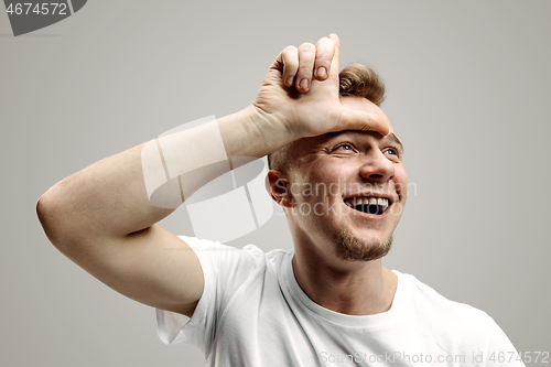 Image of Losers go home. Portrait of happy guy showing loser sign over forehead