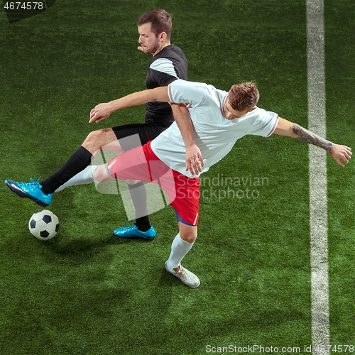 Image of Football players tackling ball over green grass background