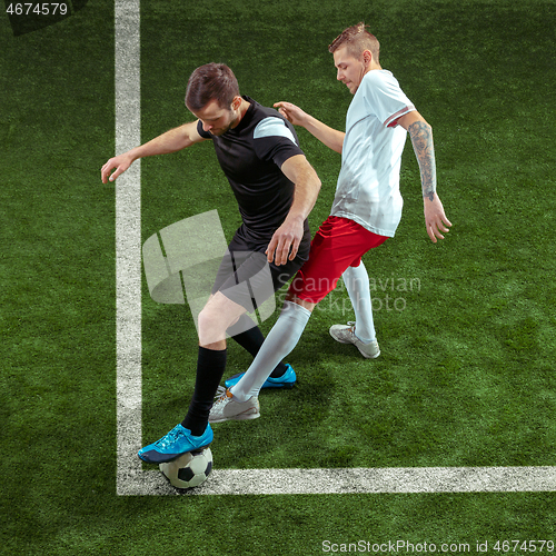 Image of Football players tackling ball over green grass background