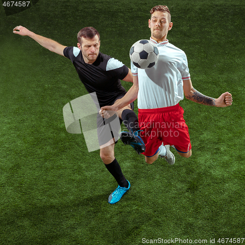 Image of Football players tackling ball over green grass background