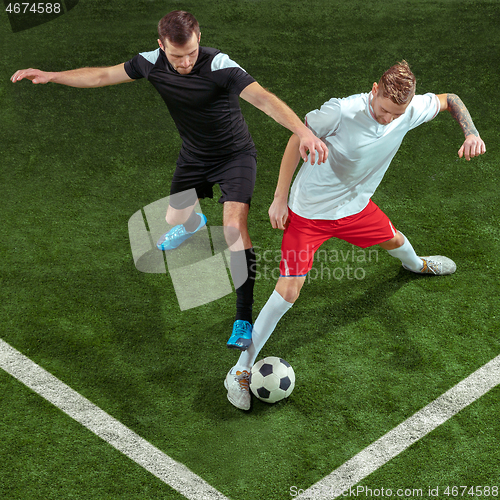 Image of Football players tackling ball over green grass background