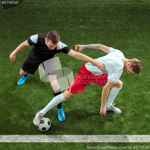 Image of Football players tackling ball over green grass background