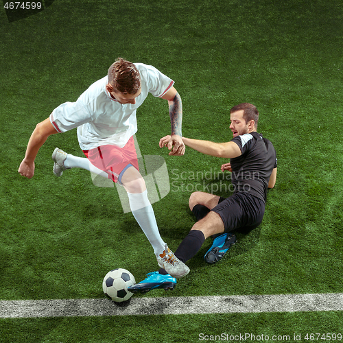 Image of Football players tackling ball over green grass background