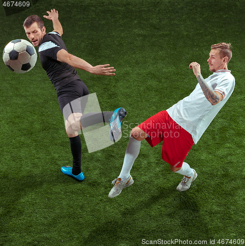 Image of Football players tackling ball over green grass background