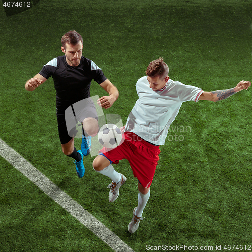 Image of Football players tackling ball over green grass background