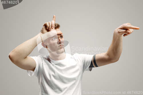 Image of Losers go home. Portrait of angry guy showing loser sign over forehead