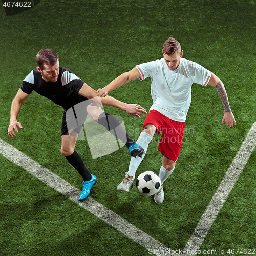 Image of Football players tackling ball over green grass background