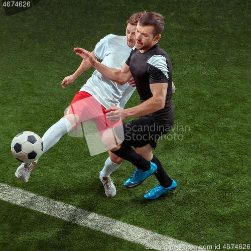 Image of Football players tackling ball over green grass background