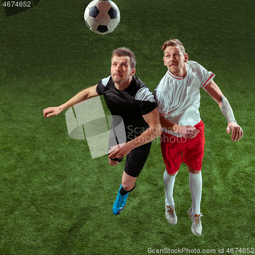 Image of Football players tackling ball over green grass background