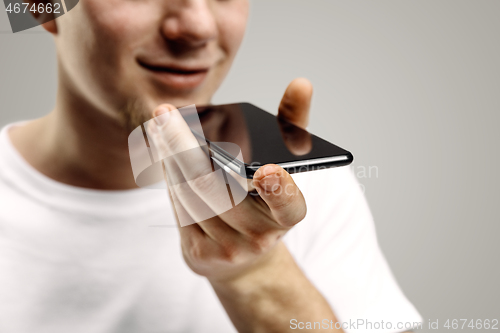 Image of Indoor portrait of attractive young man holding smartphone