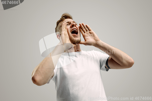 Image of Isolated on gray young casual man shouting at studio