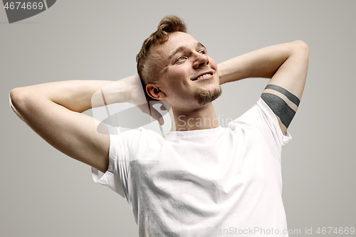 Image of The happy businessman standing and smiling against gray background.