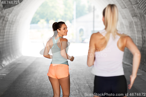 Image of women or female friends with earphones running