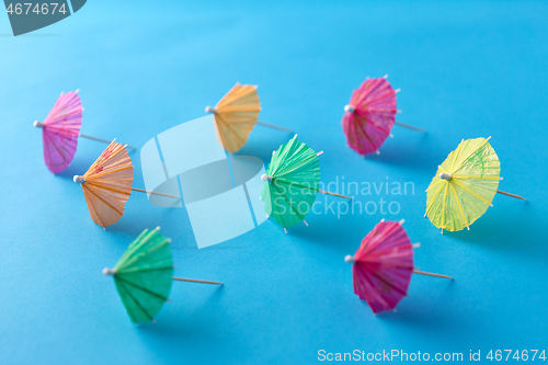Image of cocktail umbrellas on blue background