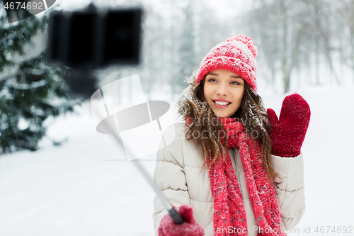 Image of young woman taking selfie by monopod in winter