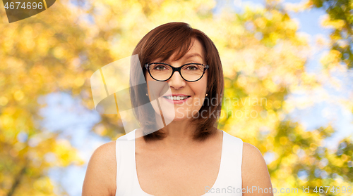 Image of portrait of senior woman in glasses over autumn