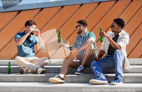 Image of man photographing friends drinking beer on street