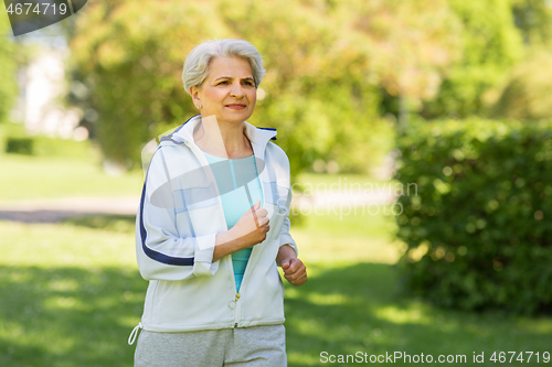 Image of senior woman running along summer park