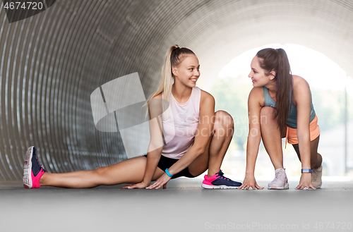 Image of women with fitness trackers stretching outdoors