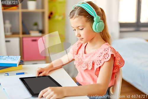 Image of girl in headphones with tablet computer at home