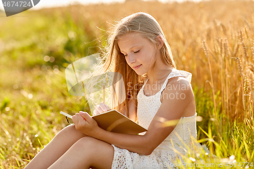 Image of smiling girl writing to diary on cereal field