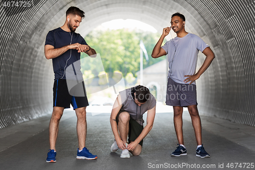 Image of male friends with earphones training outdoors