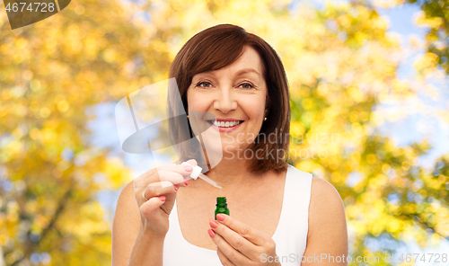 Image of smiling senior woman with bottle of serum