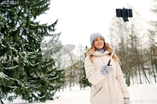 Image of woman taking picture by selfie stick in winter