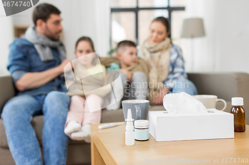 Image of medicines on table and ill family at home