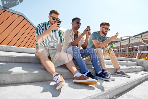 Image of men with smartphones drinking beer on street