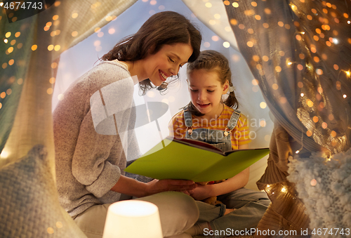 Image of happy family reading book in kids tent at home