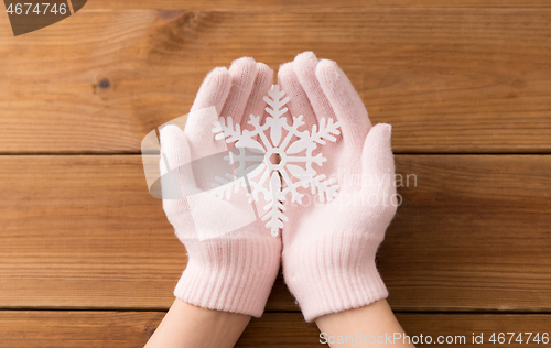 Image of hands in pale pink gloves holding big snowflake