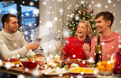 Image of happy friends drinking red wine at christmas party