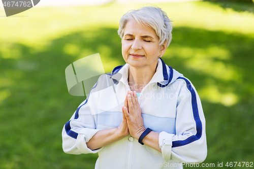 Image of happy senior woman doing yoga at summer park