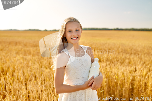 Image of happy girl with bottle of milk on cereal field