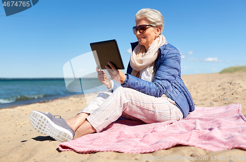 Image of senior woman with tablet computer on beach