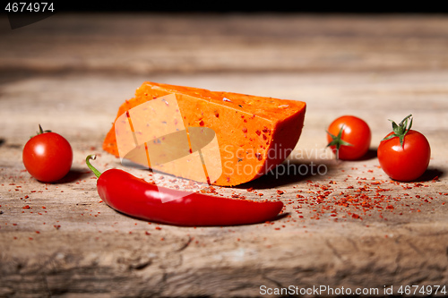 Image of Red gourmet cheese with tomatos and parika on rough wooden planks