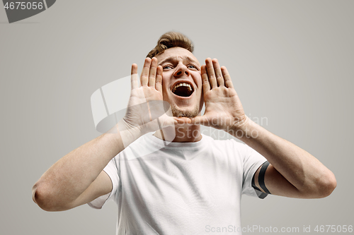 Image of Isolated on gray young casual man shouting at studio