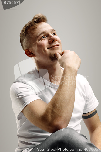 Image of The happy businessman standing and smiling against gray background.