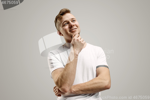 Image of The happy businessman standing and smiling against gray background.