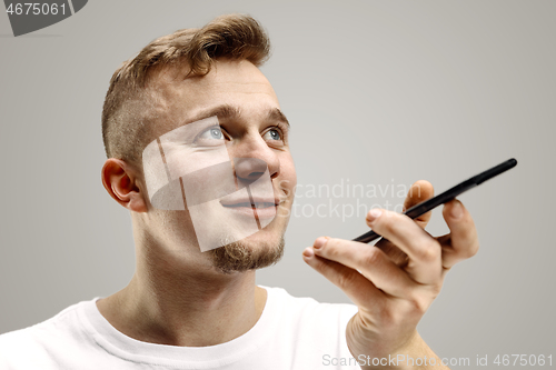 Image of Indoor portrait of attractive young man holding smartphone