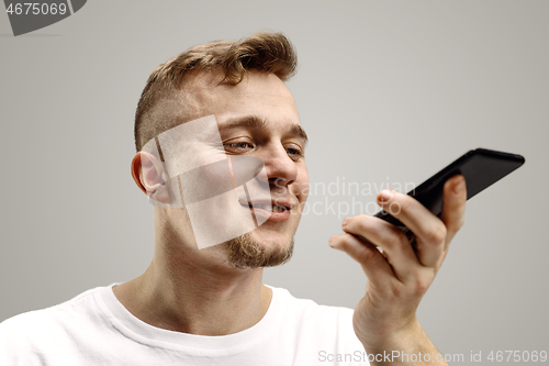 Image of Indoor portrait of attractive young man holding smartphone
