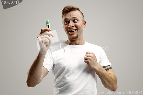 Image of Happy man looking at pregnancy test at studio