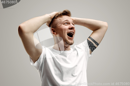 Image of The young emotional angry man screaming on garay studio background