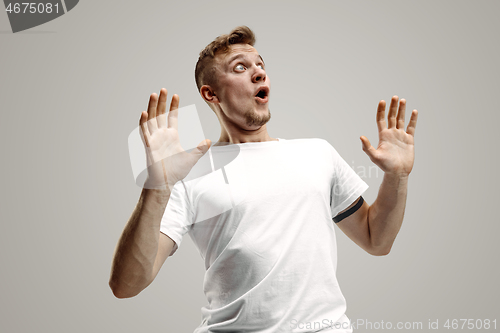 Image of The young attractive man looking suprised isolated on gray