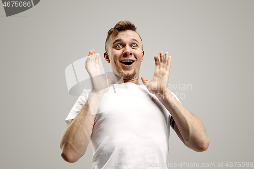 Image of The young attractive man looking suprised isolated on gray