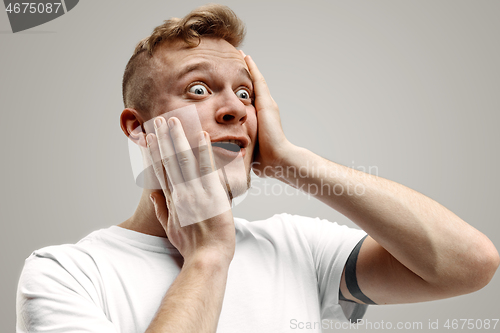 Image of The young attractive man looking suprised isolated on gray