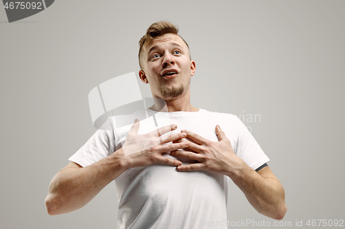 Image of The young attractive man looking suprised isolated on gray